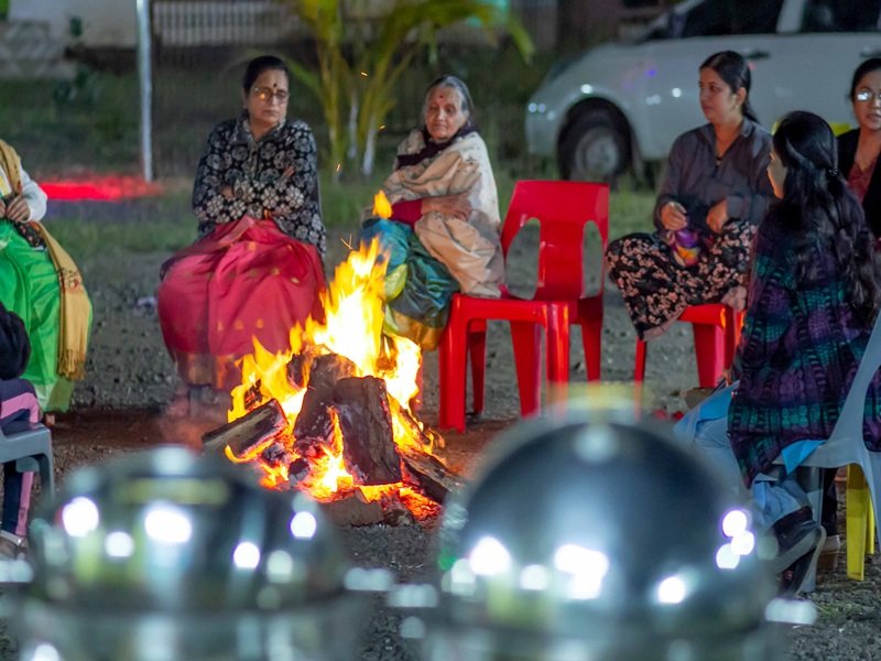Guests enjoying a campfire evening at a resort in Bhandardara