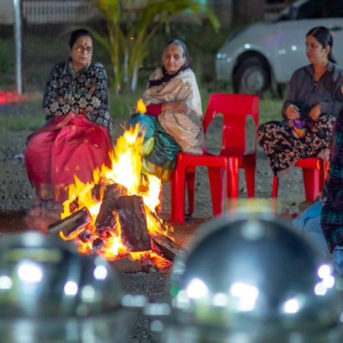 Guests enjoying a campfire evening at a resort in Bhandardara